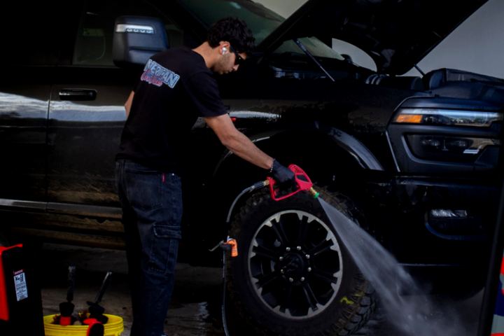 Lavado a presión de la rueda de una camioneta, con el capó abierto
